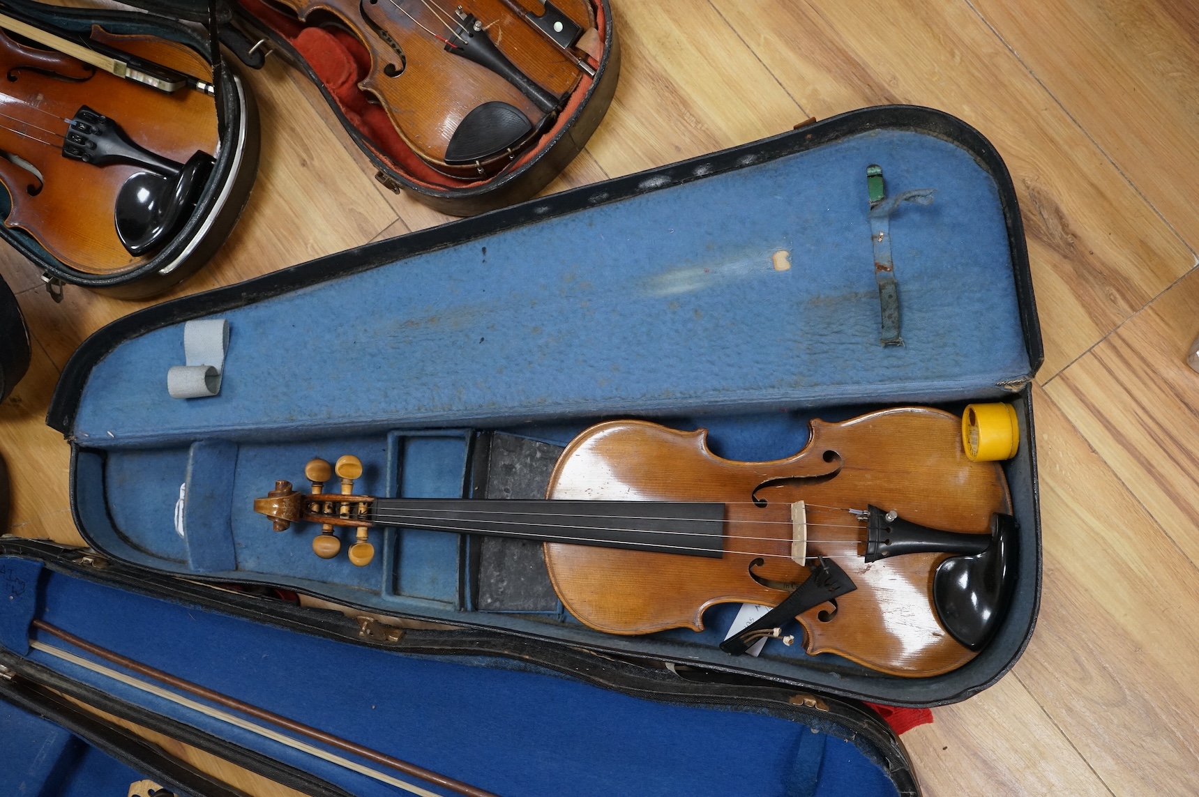 Five cased 20th century violins, including; a German violin, two Czech violins, a three-quarter size violin with a label for Bienfait, and a Romanian quarter size violin, all in cases or the remains of cases.